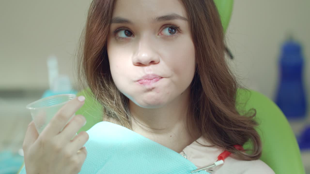 치과의사의 의자에서 입을  ⁇ 고 있는 젊은 여자를 닫으세요.