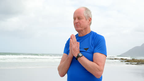 Front-view-of-old-caucasian-man-meditating-at-beach-4k