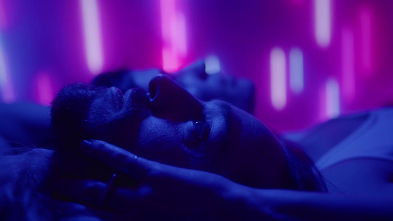 Coppia sdraiata sul letto in una stanza con luce al neon