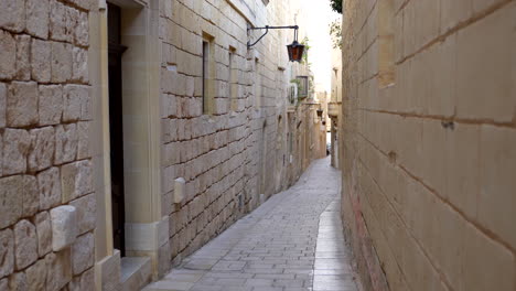 Pov-of-narrow-alley-surrounded-by-old-historic-buildings-during-daytime