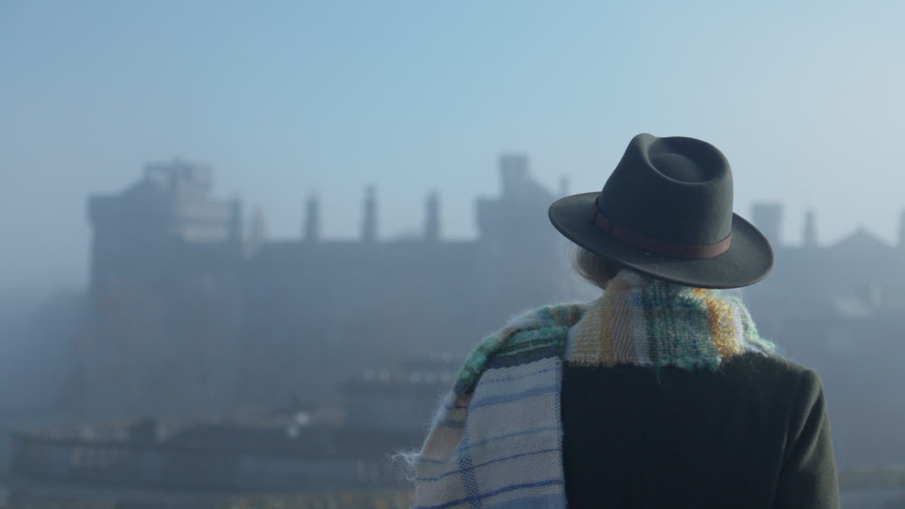 mujer mirando el castillo medieval desde la azotea en un día brumoso