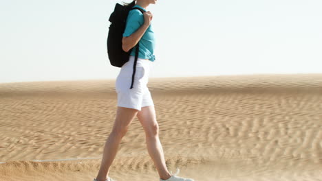 woman with sunglasses and backpack walking