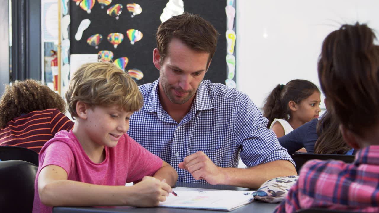 maestro y joven escolar mirando el cuaderno en clase