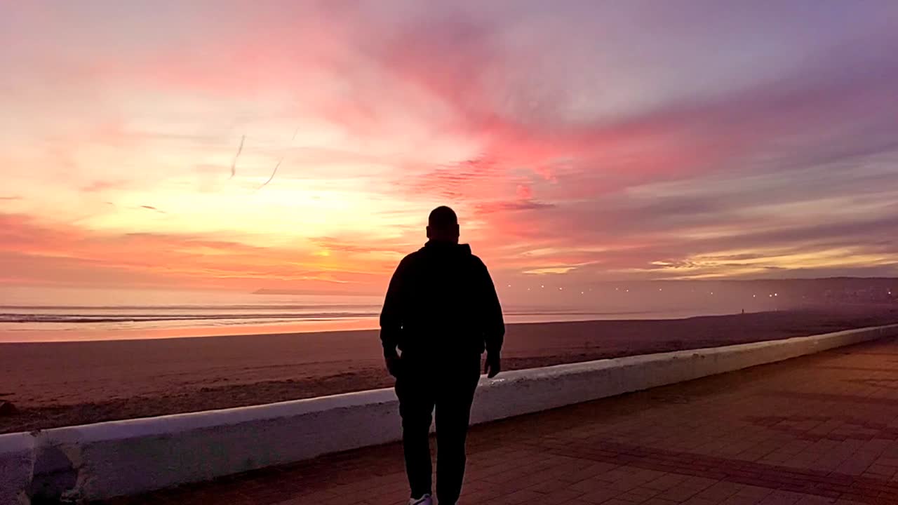 cinematográfica en cámara lenta vista trasera de un hombre viendo la puesta de sol dorada en el mar en en playa del carmen, ciudad turística costera de méxico