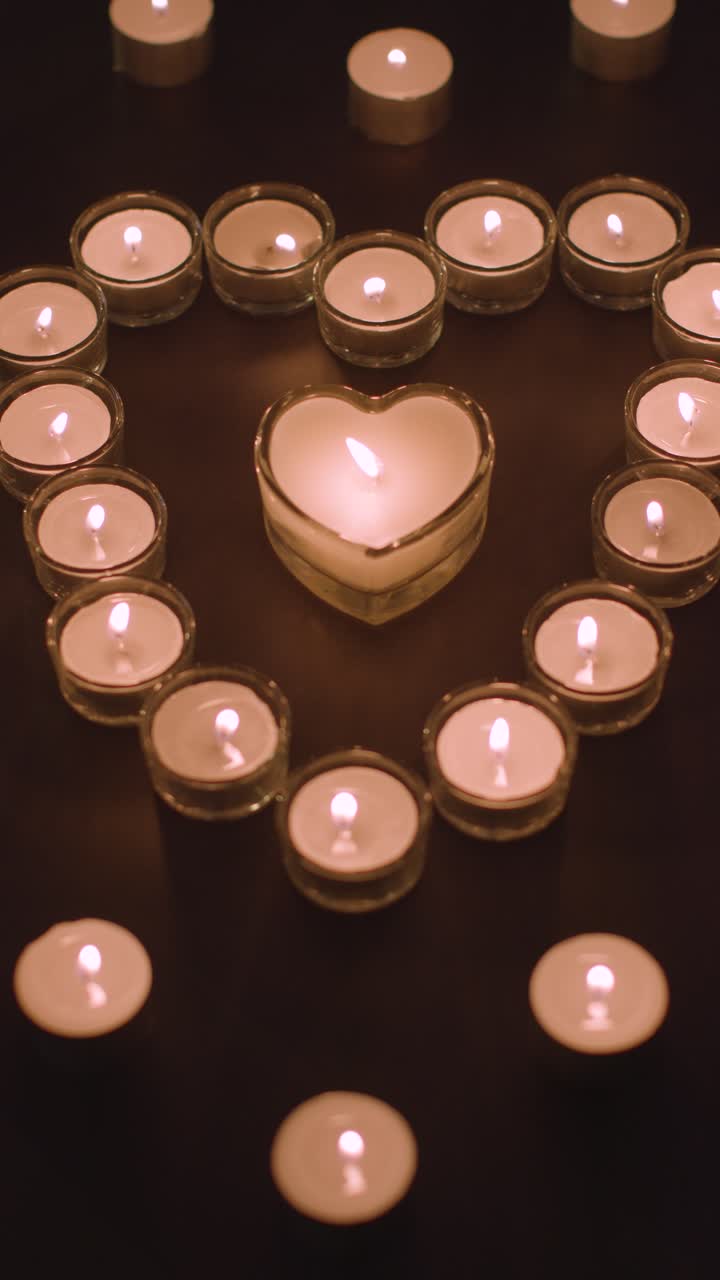 Video verticale di candele romantiche bianche a forma di cuore su sfondo nero 2