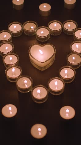 Vertical-Video-Of-Romantic-White-Candles-In-the-Shape-Of-A-Heart-On-Black-Background-2