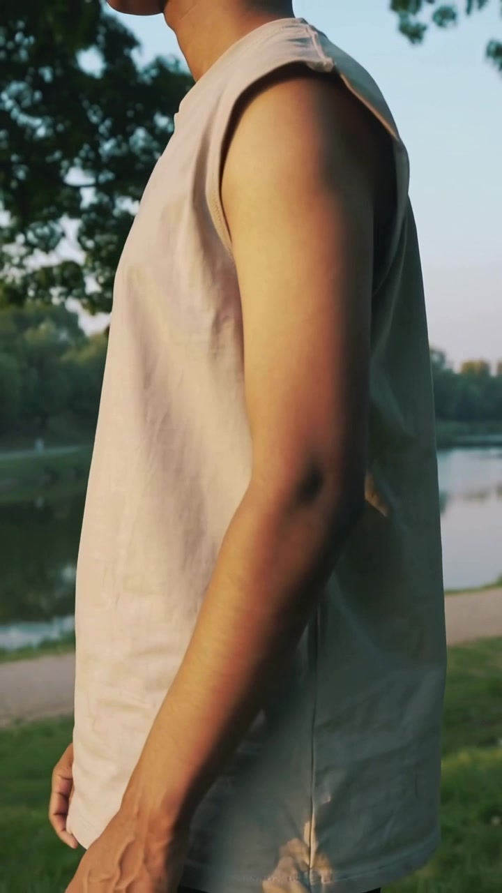 Video verticale: Telecamera che si allontana mostrando un uomo con canotta beige che si gira verso il lago, osservando la riva