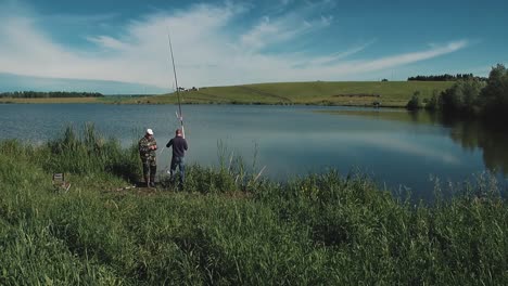 two young guys are fishing on the lake