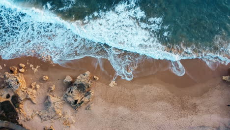 aerial top down shot of rocky beach and ocean, waves crashing