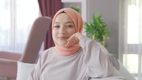 happy muslim woman in hijab smiling at camera at home.