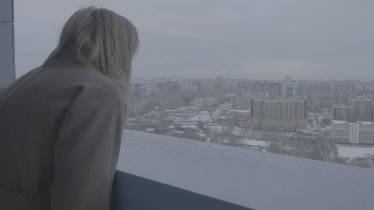 mujer contemplando la vista de la ciudad en un día de invierno nevado