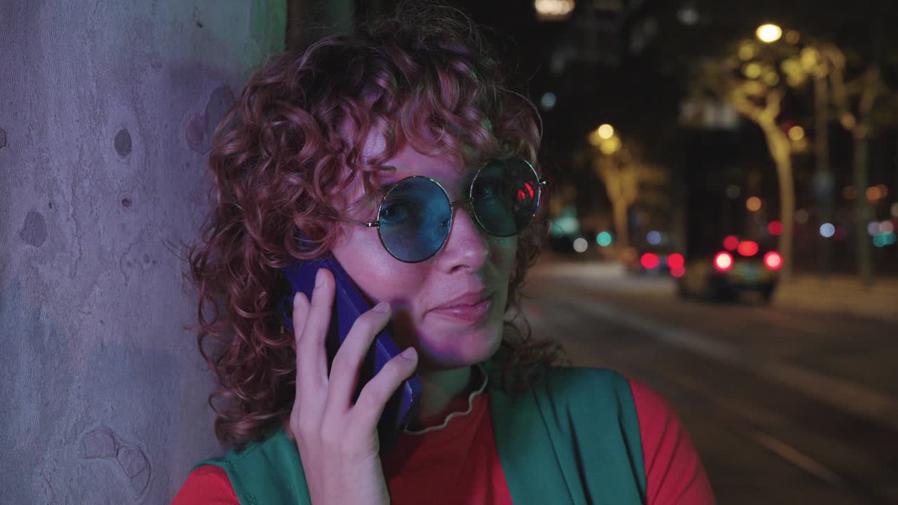 Woman with curly hair talking on phone at night