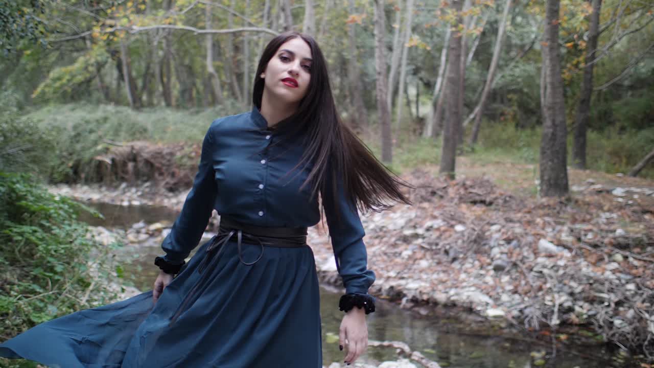 Una bellissima modella gotica balla e piroetta al rallentatore nel bosco.