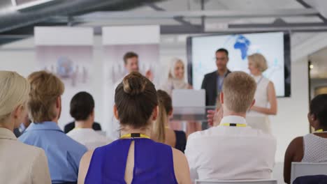 Female-speaker-and-applauding-audience-and-colleagues-at-a-business-conference