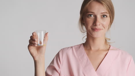 caucasian female doctor holding flask with pills.