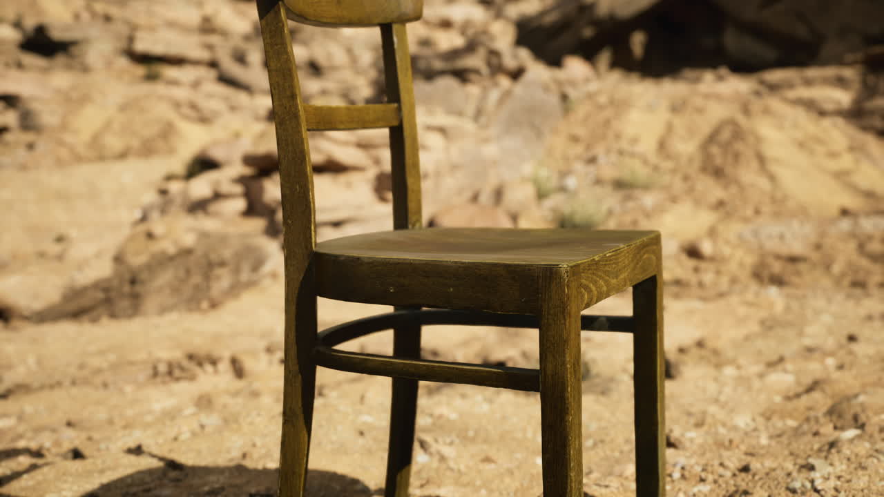 Wooden chair placed on rocky terrain under bright sunlight