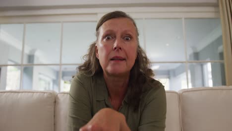 senior caucasian woman talking and gesturing during a video call, sitting in living room