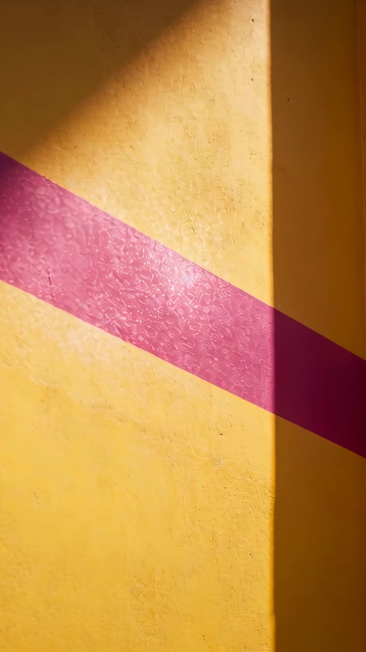 Vertical video: Cam panning right, showing textured wall design, pink band meeting shadow at corner