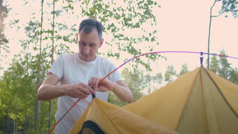 Portrait-of-a-man-setting-up-a-tent-in-the-woods-in-slow-motion