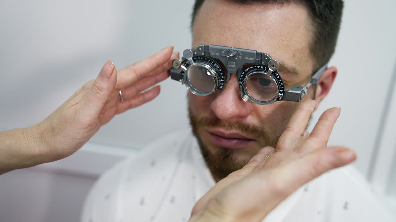 Doctor checks man's sight with optical trial frame. Portrait of a young male patient testing his eyesight in ophthalmological center.