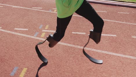 disabled mixed race man with prosthetic legs running on race track