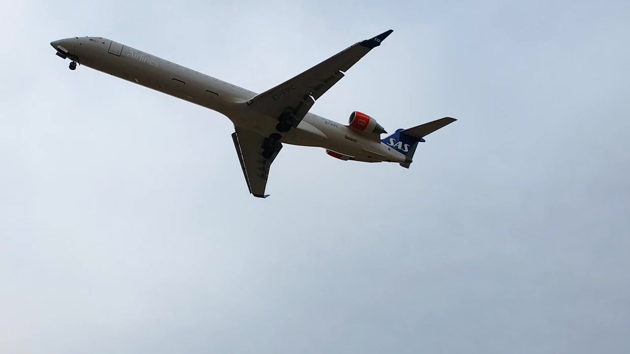Passagem próxima de avião da SAS pousando no Aeroporto de Copenhague sob céu cinzento