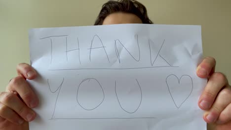 Young-Male-University-Student-Holding-Up-Thank-You-Sign-During-Video-Lecture