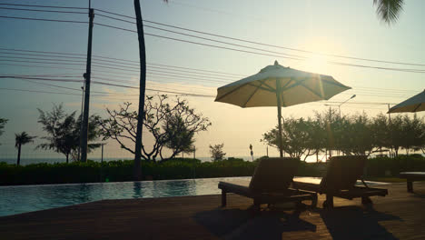 umbrella-with-bed-pool-around-swimming-pool-with-ocean-sea-background---holiday-and-vacation-concept