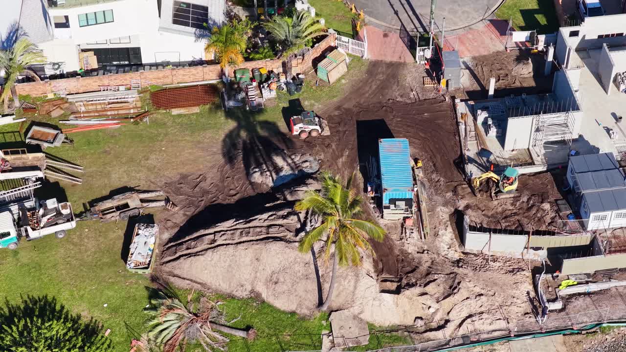 Drone footage captures construction workers and machinery at a residential site under sunny conditions in Gold Coast, Australia