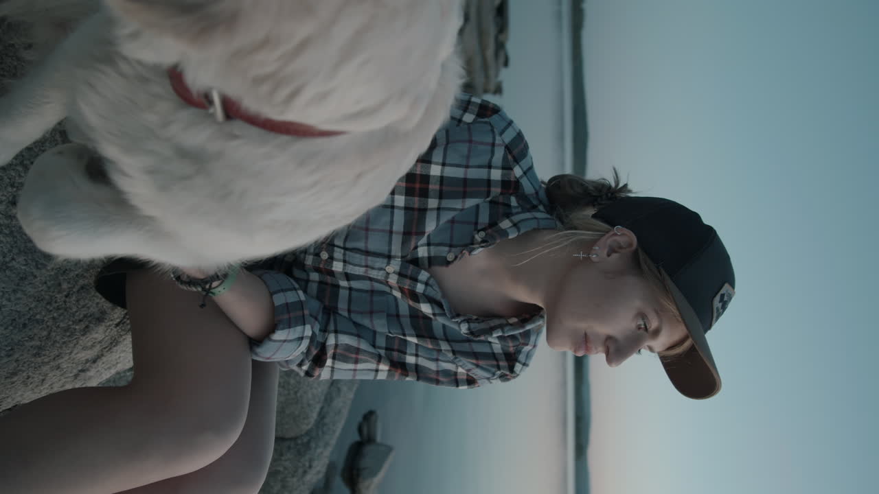 mujer y perro sentados junto al lago por la noche