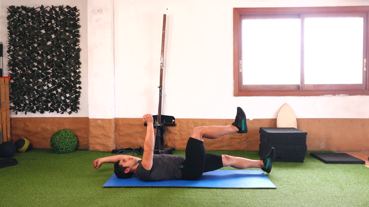 trainer during online class doing variant of abdominal exercise on blue mat