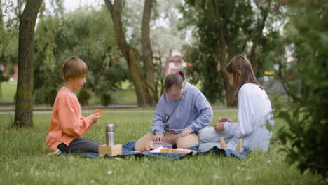 little girl with down syndrome sitting in the park with her friends. they are building wooden models