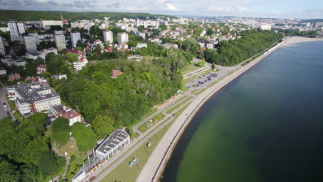 Vista-Aérea-Que-Muestra-La-Costa-Del-Mar-Báltico-En-La-Ciudad-De-Gdynia-Con-Bloques-De-Apartamentos,-Bosques-Y-El-Centro-De-La-Ciudad-Como-Telón-De-Fondo