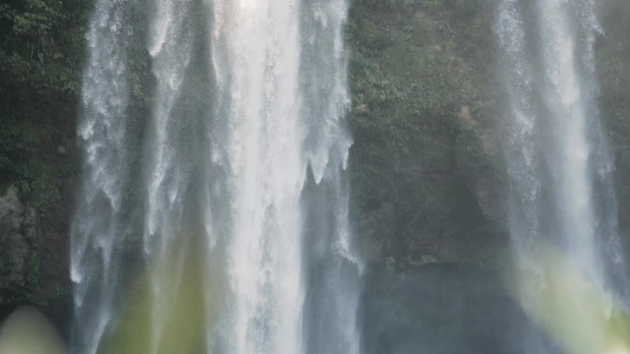 cascada que cae desde un alto acantilado rocoso hacia el río en el bosque maya, méxico