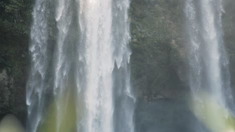 waterfall plunging from high rocky cliff down into the river in mayan forest, mexico