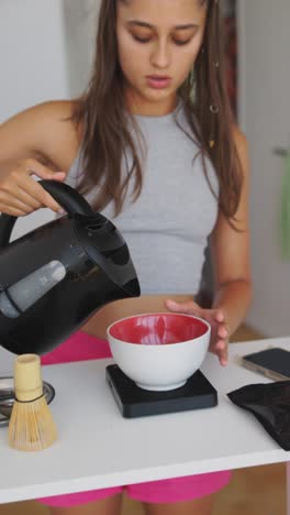 person pouring hot water from a kettle into a bowl on a scale