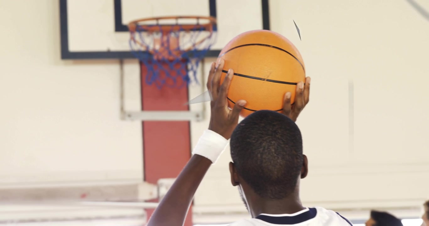 Giocatore di basket che alza la palla sopra la testa sotto il canestro, rilasciando un tiro che segna con sovrapposizioni triangolari