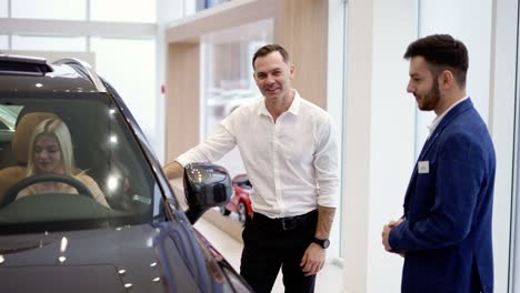 Blonde-female-testing-buying-car-from-inside-during-visit-auto-dealership