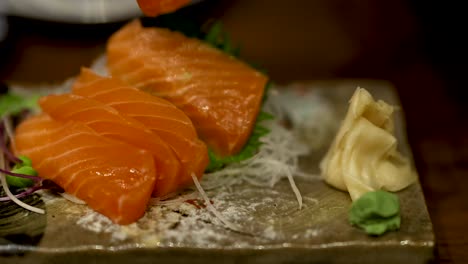 chopsticks picking up salmon sashimi in dubai