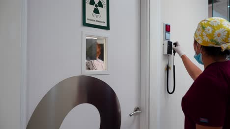 el dentista fuera de la sala de rayos x comprobando el proceso de su paciente