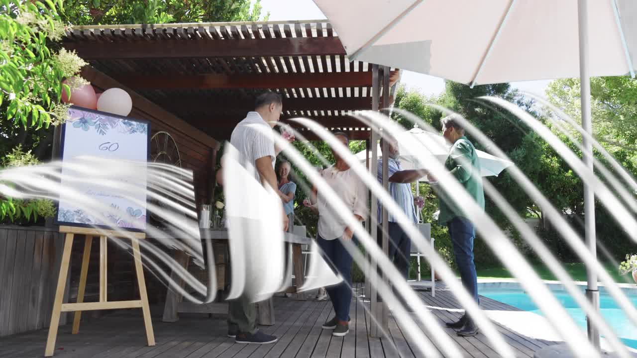 Group meeting under pergola circling table, man raising glass sparking 60 party, white sweep hiding