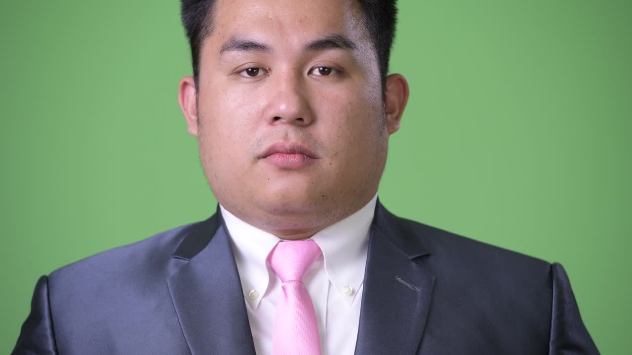 초록색 배경에 젊은 잘생긴 과체중 아시아 사업가