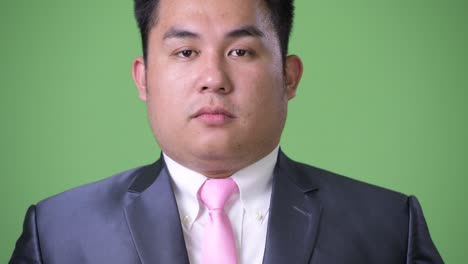 joven apuesto hombre de negocios asiático con sobrepeso contra un fondo verde