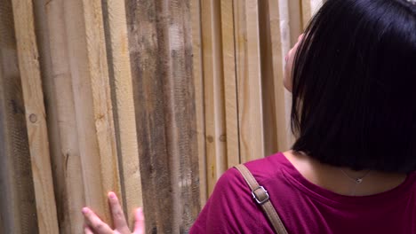 Japanese-Female-examining-wooden-planks-at-hardware-store