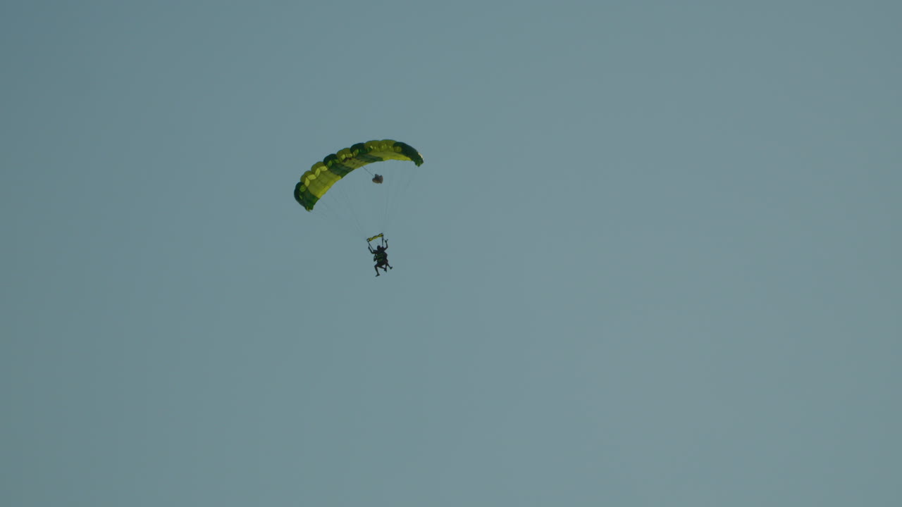 Tracking shot of skydiver flying in the air against blue sky in Poland - Wide shot bottom up