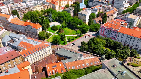 Lovely green city park near the old houses. A tram moves by the railway along the city. Old town in Bratislava, Slovakia. Aerial view
