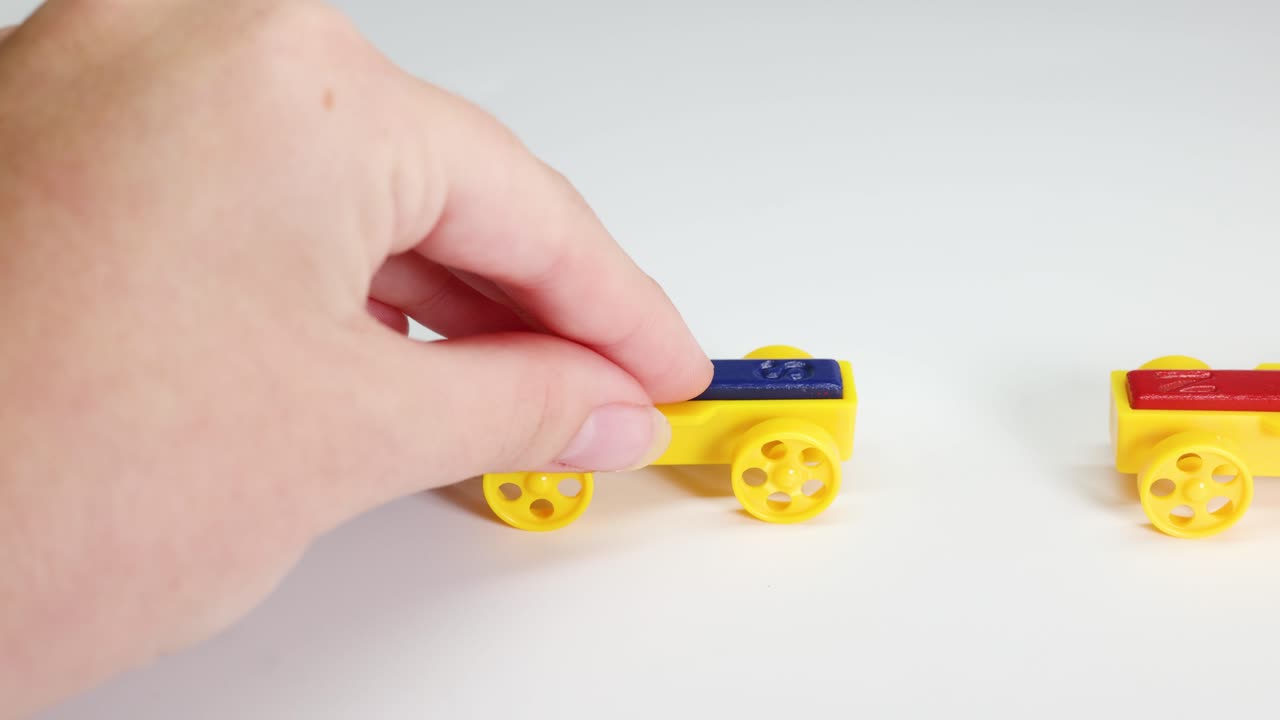 Hands manipulate colorful toy cars with magnets, illustrating magnetic attraction and repulsion on a white background