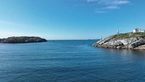 Sailing out from Henningsvaer harbor in Lofoten with sea channel, beacon and horizon on a sunny calm day