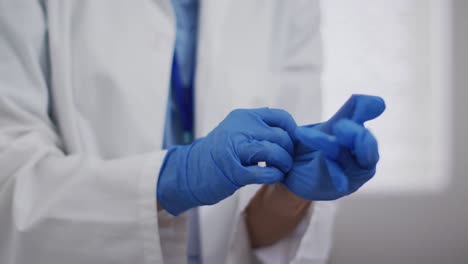 Portrait-of-mixed-race-female-doctor-taking-protective-gloves-off