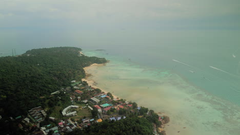 aerial view of a tropical island coastline with resorts and boats